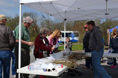 A picture of Arbor Day, a Franklin TN event at Pinkerton Park showing people standing outside under a white tent.