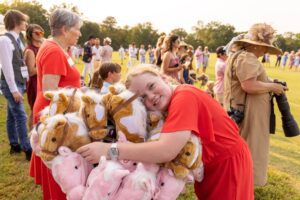 Girl hugging stick horses at Chukkers for Charity.