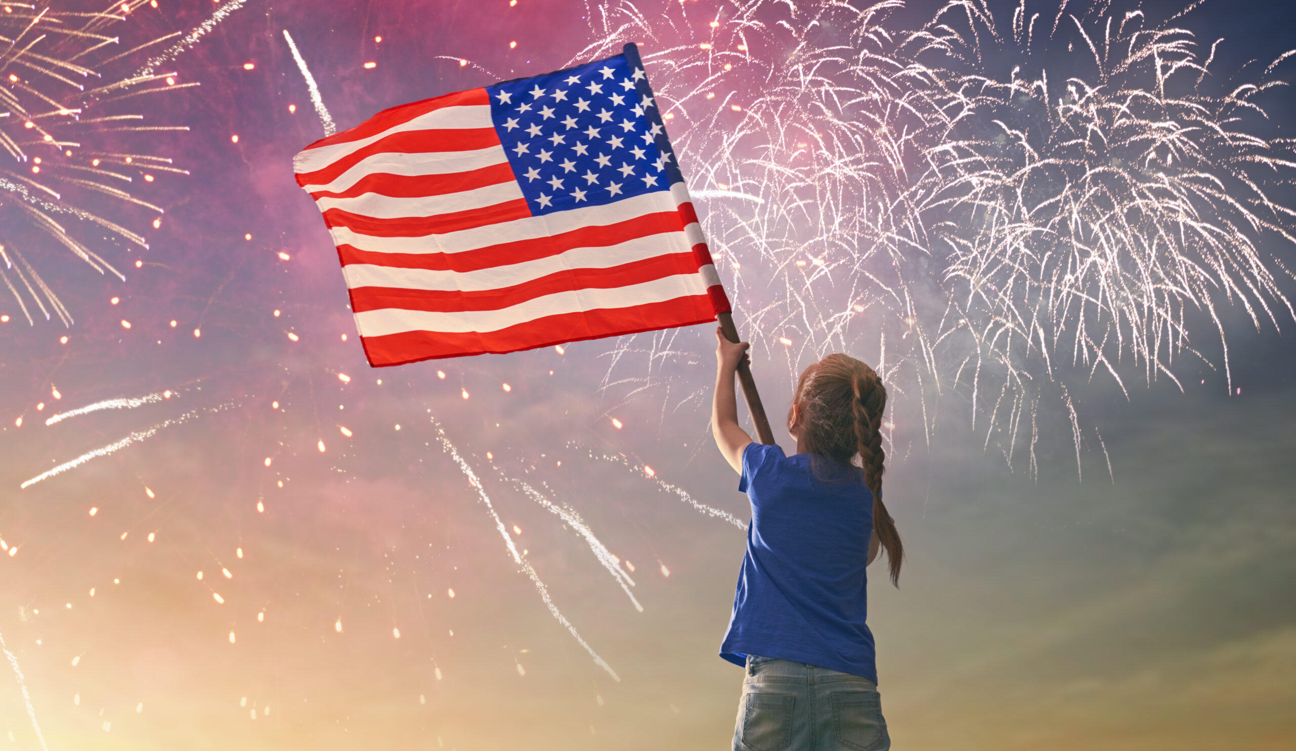 4th of July celebration in Nashville, Tennessee, child watching fourth of July fireworks show while holding a US flag.