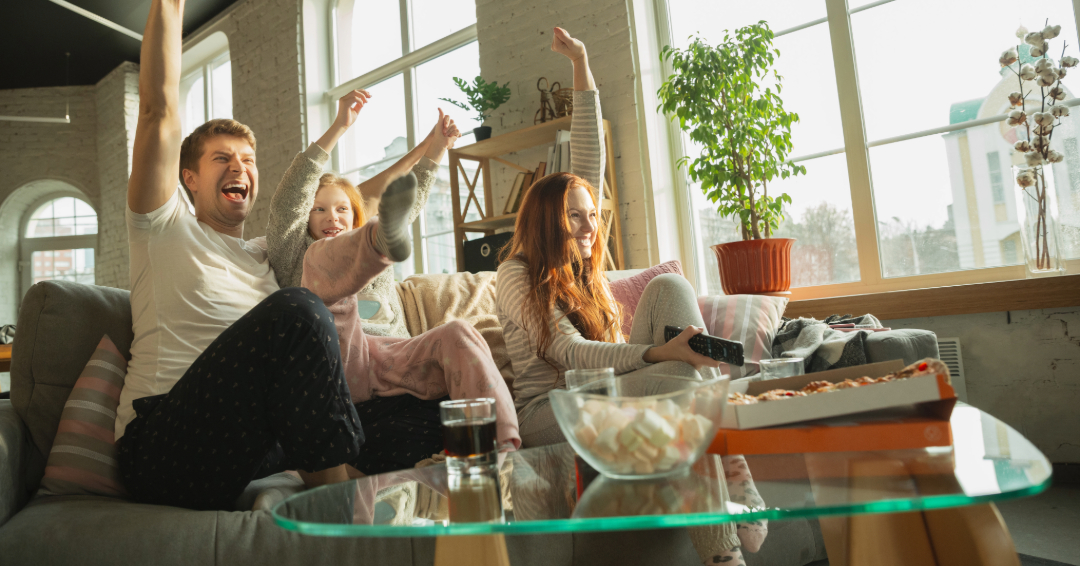 Family watching the 2024 Olympics at home with carryout food.