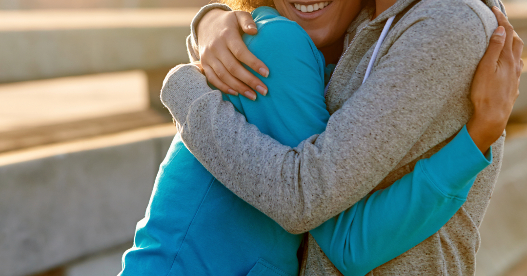 Women in sweatshirts hugging one another.