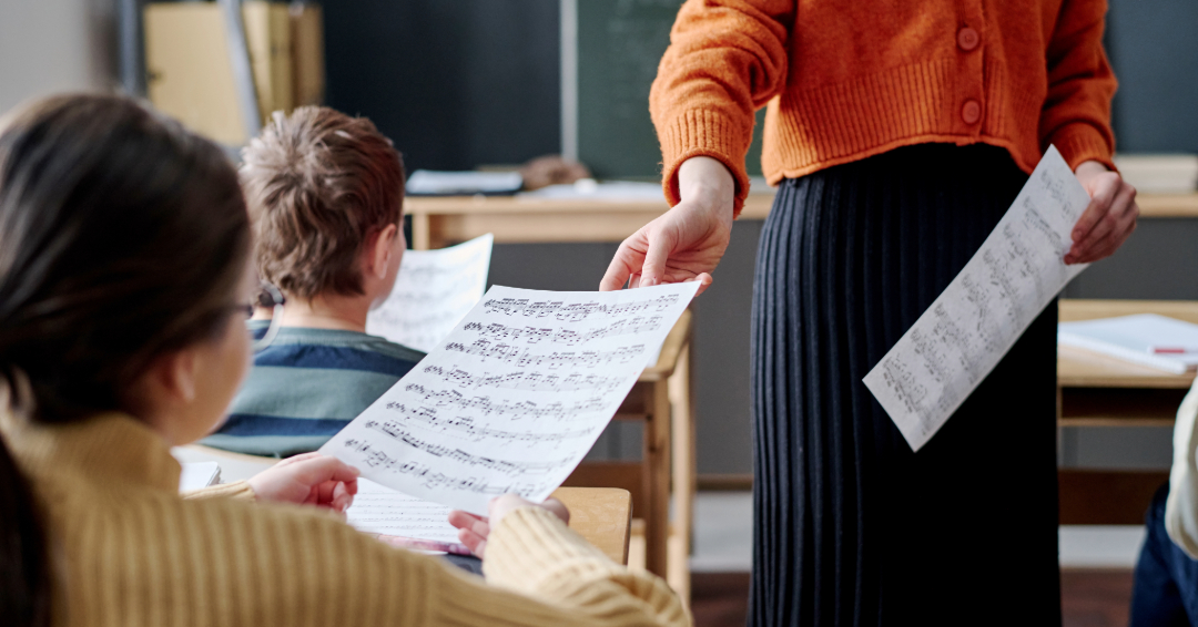 A music teacher hands students sheet music.