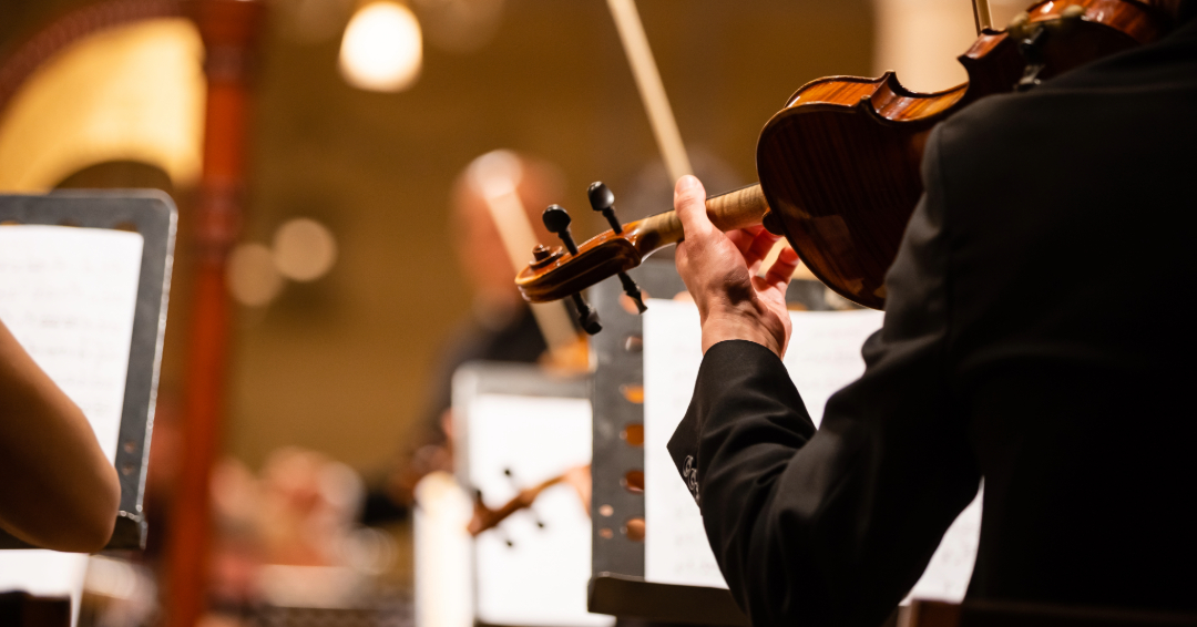 A scene of an orchestra: violin, music stands, sheet music.