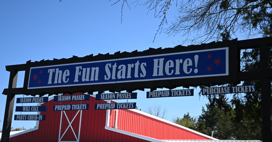"The Fun Starts Here" blue sign in front of a red barn at Lucky Ladd Farms in Eagleville, Tennessee.