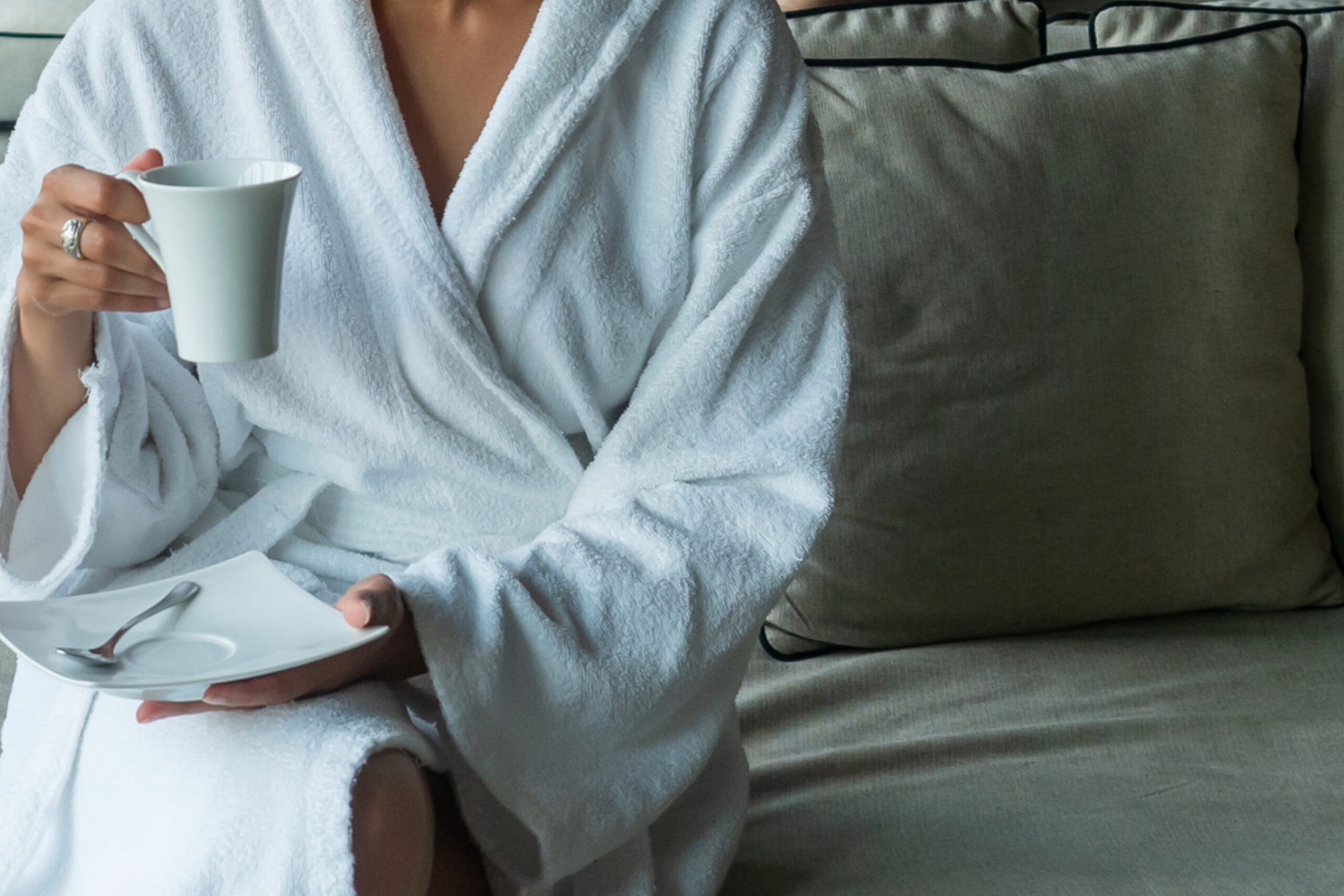 Staycation Franklin & Williamson County, TN, A woman in a Franklin hotel holds a mug and a small plate, wearing a robe, representing a relaxing staycation.