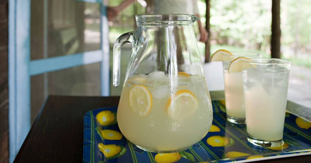A pitcher of fresh lemonade is ready to be served on a porch in summertime. 