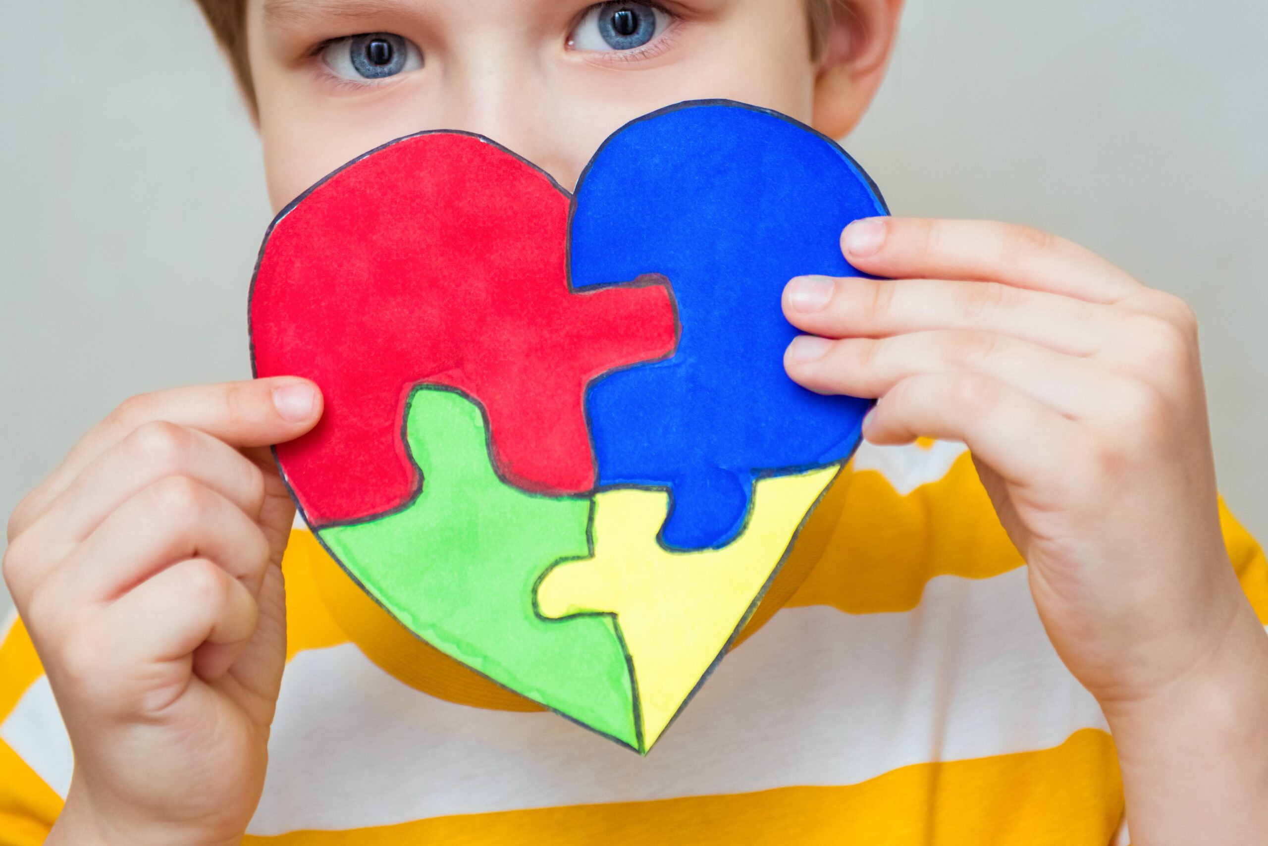 A young boy holds up a puzzle-piece heart, representing cognitive disability resources in Williamson County, Tennessee.