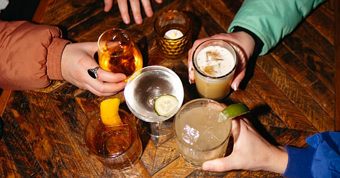 A group of friends cheers their cocktails at Urban Cowboy Public House, a bar in East Nashville, Tennessee. 