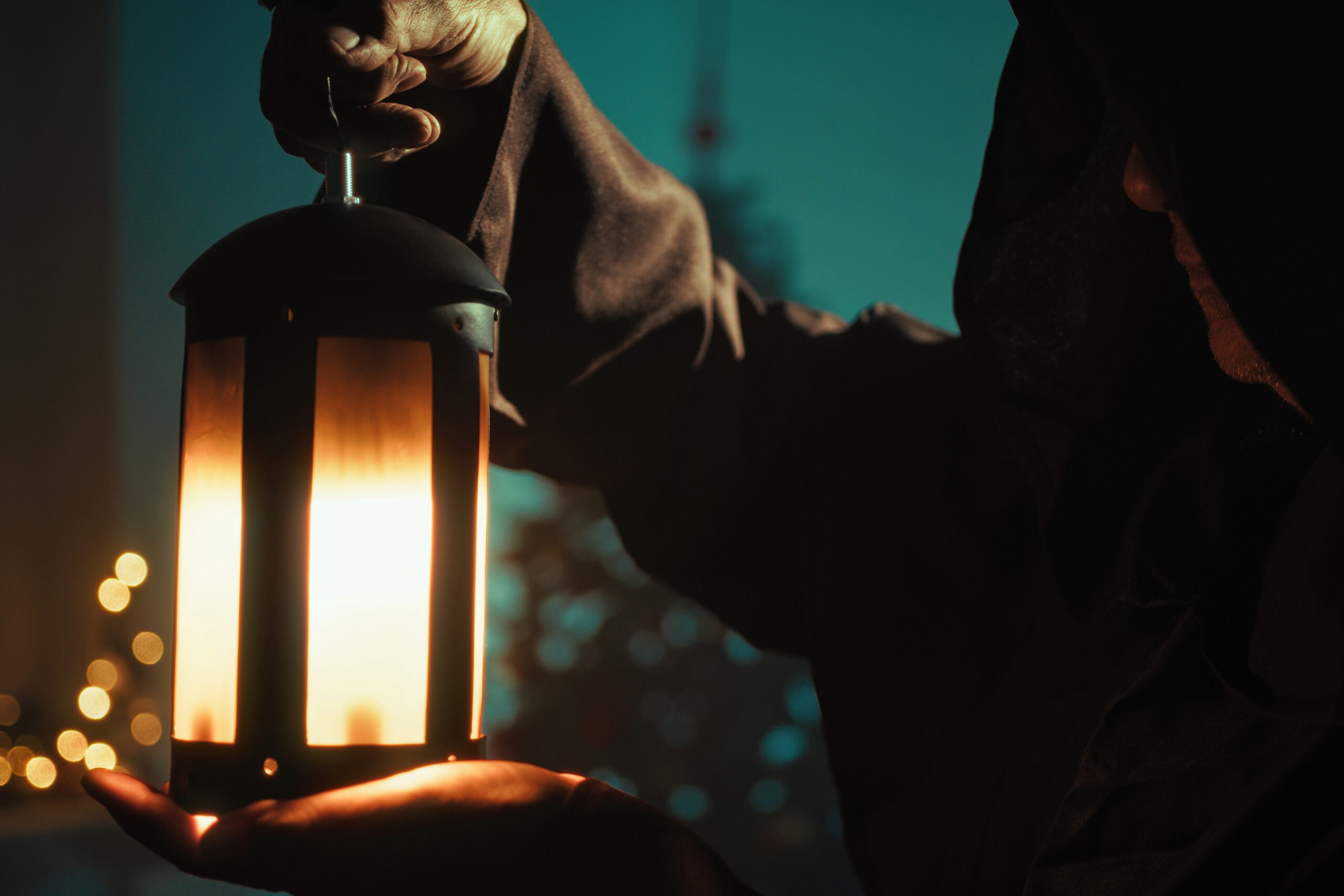 A cloaked figure holds a glowing lantern in the dark, evoking the eerie atmosphere of a Franklin Ghost Tour and the haunted history of downtown Franklin, Tennessee.